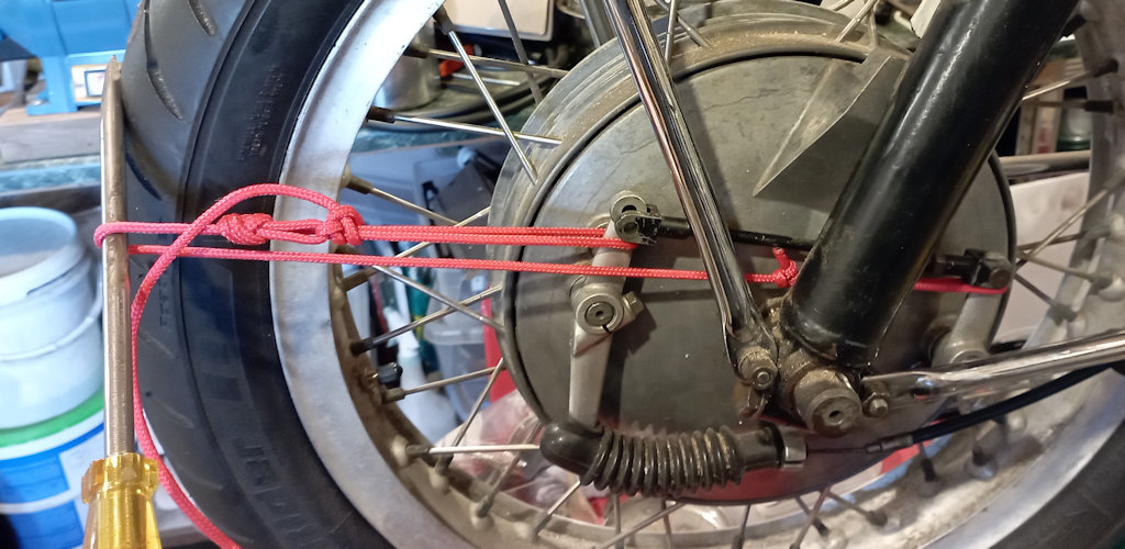 Using a cord tensioned by a lever to adjust the front brake.