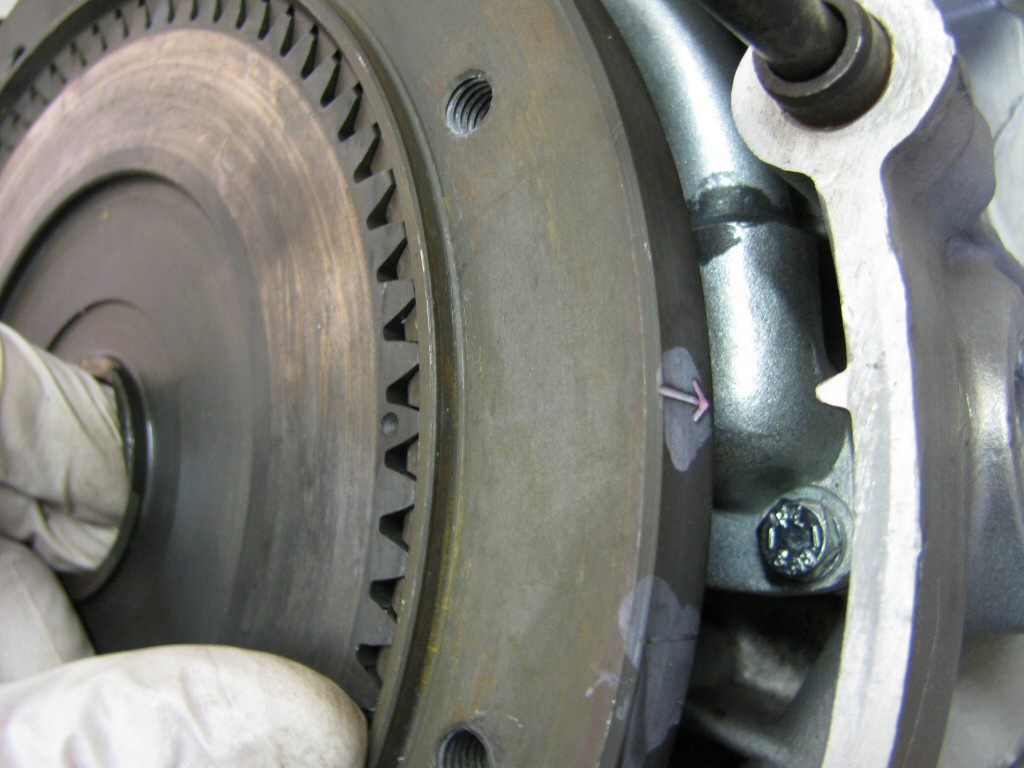 Fit the pressure plate. Note that the dot on the tooth must align with the arrow on the flywheel. Doing so is necessary to make sure the springs fit into the approprieate recess.